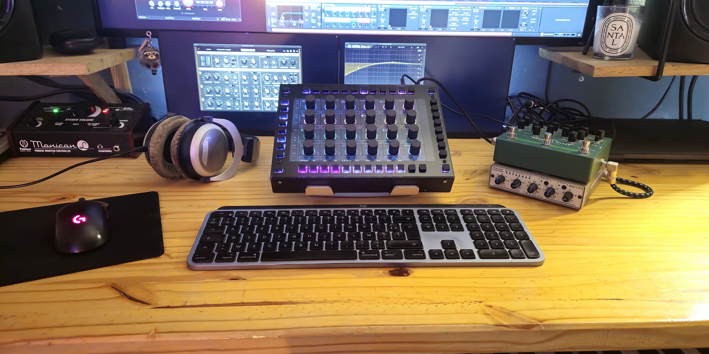 KARL on a wooden desk next to a keyboard, headphones and studio monitors